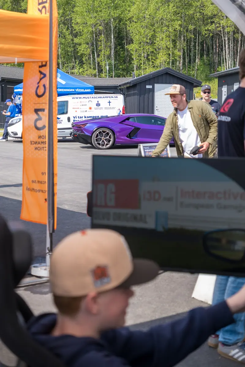 Crowd gathered around racing simulators in a paddock